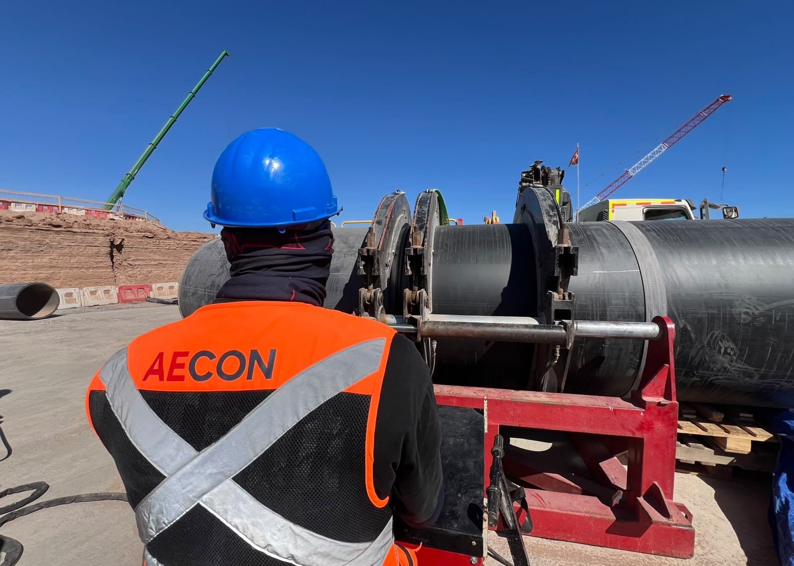 Trabajador de AECON con casco azul frente a una máquina de termofusión de tubería HDPE
