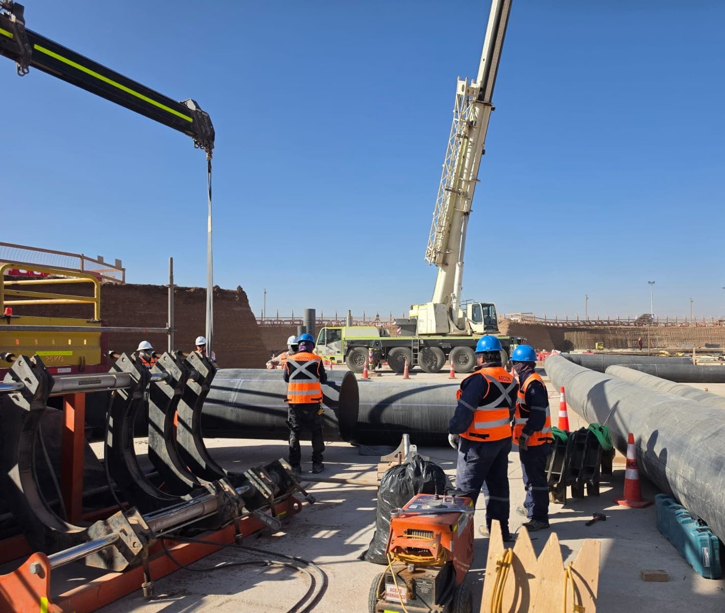 Trabajadores de AECON junto a tuberías HDPE y una grúa en faena
