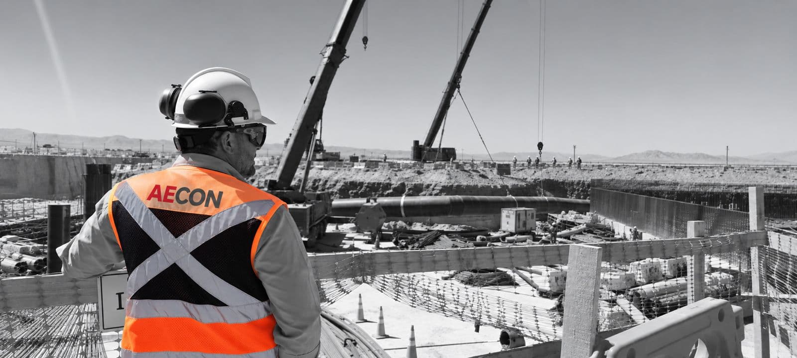 Trabajador de AECON supervisando montaje de tuberías y grúas en faena, Antofagasta