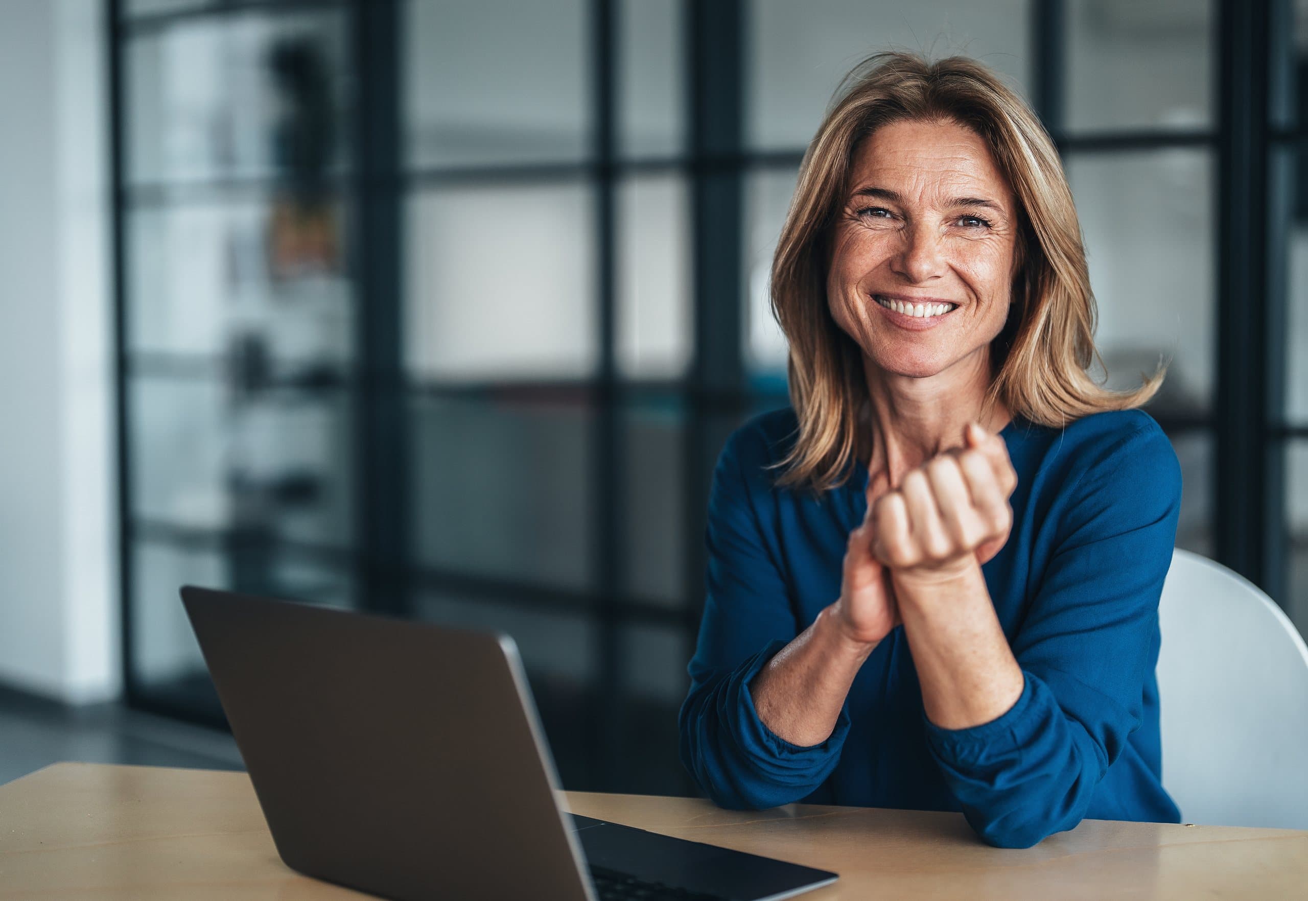 Profesional sonriendo frente a su laptop en una oficina